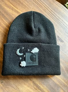 a black beanie hat with an elephant patch on it sitting on top of a wooden table