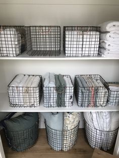 the shelves are organized with baskets and blankets for storage in this closet, which is also filled with folded linens