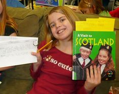 two girls are holding up their books in front of them