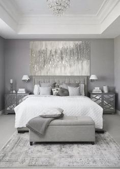 a large white bed sitting in a bedroom next to a chandelier