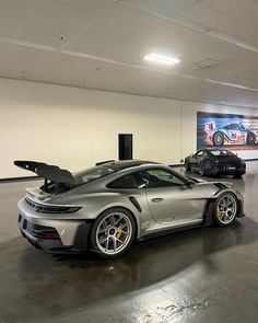 two cars are parked in a large garage