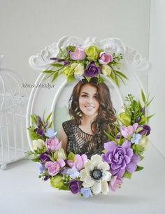 a white frame with purple and green flowers in the shape of a woman's face