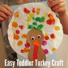 a child holding up a paper plate with a turkey on it and the words easy toddler turkey craft