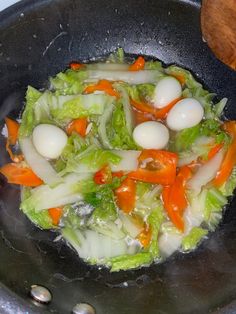 vegetables are cooking in a wok on the stove