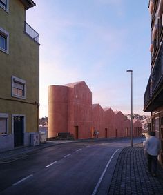 a person walking down the street in front of some buildings with red walls and windows