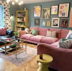 a living room with pink couches and pictures on the wall above them, along with other furniture