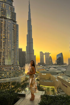 a woman standing on top of a building next to tall buildings