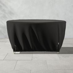 a black table cover sitting on top of a tile floor next to a white wall