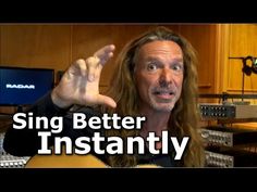 a man with long hair is holding up his hand and looking at the camera while in front of a recording studio