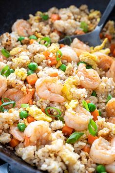 a skillet filled with shrimp, rice and peas