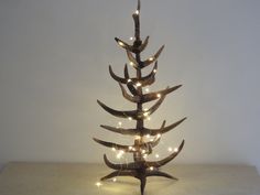 a christmas tree made out of antlers with lights on it's branches is shown in front of a white wall