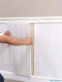 a man sitting on the floor with his feet up against a white paneled wall