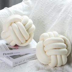 two white decorative objects sitting on top of a bed next to a stack of books