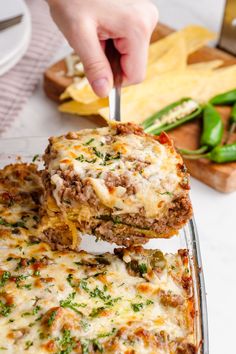 someone is cutting into a lasagna casserole with cheese and green peppers