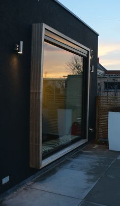 an open window on the side of a black building at sunset or dawn with no one in it