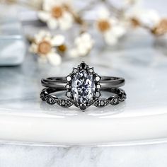 a white diamond ring sitting on top of a marble table next to flowers and glass vases