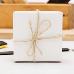 a white gift box wrapped in twine and tied up with a brown string on top