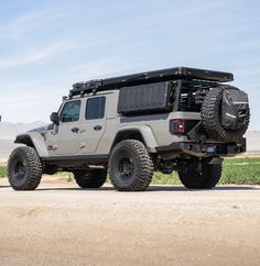 the jeep is parked on the side of the road in front of some grass and dirt