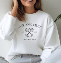 Elevate your tennis style with our Tennis Club sweatshirt, a cozy and personalized unisex pullover that makes the perfect custom gift for tennis enthusiasts. Whether you're surprising a roommate, impressing your girlfriend, making dad's day, or delighting a stepmom, this sweater is a stylish blend of comfort and personalization for tennis-loving women and girls alike. HOW TO ORDER 1. Select size 2. Select color 3. Enter your custom text and year in the personalization box. SWEATSHIRT COLORS - Please refer to the color chart to view all individual colors. The drop down menu automatically shows all colors available to purchase. Not all colors listed on the chart are available for this apparel design. TEXT/DESIGN COLORS - Text and/or design colors could vary depending on which apparel color y Tennis Club Sweatshirt, Tennis Sweatshirt, Tennis Sweater, Sweatshirt Colors, Tennis Style, Tennis Club, Club Sweatshirts, Tennis Clubs, Design Text