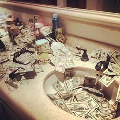 a sink filled with lots of money sitting on top of a counter next to a mirror