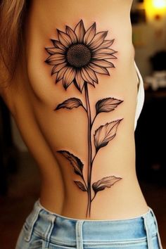 a sunflower tattoo on the back of a woman's rib - up stomach