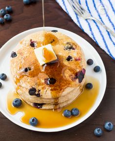 blueberry pancakes with butter and syrup on a white plate