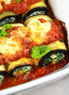 a casserole dish filled with eggplant, cheese and spinach covered in sauce