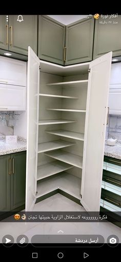 an open cabinet in the middle of a kitchen with marble counter tops and green cabinets