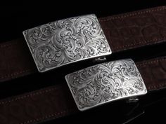 One of our most popular buckles, this understated piece by Comstock Heritage is perfect for those just starting their buckle collections, or for more formal occasions. It’s made from heavy-gauge, hand-engraved Sterling silver, and its rectangular face is adorned with beautiful, delicate scrollwork. This buckle can be paired easily blue jeans or be worn with dressier slacks. Smaller size measures 1 ⅝” x 2 ⅝” and fits all 1 ¼" belt traps Larger version measures 1 ⅞” x 2 ¾" and fits all 1 ½" belt s Luxury Engraved Silver Belt Buckles, Classic Formal Engraved Belt, Classic Formal Belts With Engraved Details, Classic Formal Belt With Engraved Details, Classic Engraved Belts For Formal Occasions, Luxury Formal Jewelry With Silver Buckle, Classic Silver Formal Belt, Silver Classic Formal Belt, Formal Engraved Belt Buckles