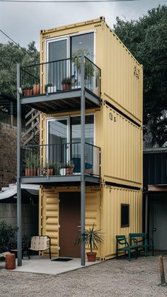 a yellow shipping container with two balconies on the top floor and balcony above it