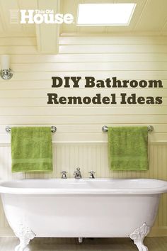 a white bath tub sitting under a window next to two green towels on top of it