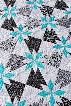 a close up of a quilt on a bed with black and white designs in the middle