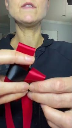 a woman is tying a red tie with her hands