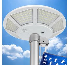 an american flag is hanging on the side of a street light with blue sky and clouds in the background