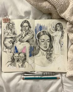 an open notebook with drawings of women on it and a pen laying next to it