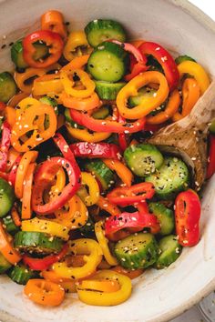 a white bowl filled with lots of different types of peppers and cucumber slices