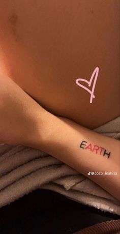 a woman's arm with the word earth tattooed on it