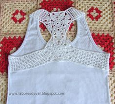 a white tank top with crochet on it sitting on a quilted surface