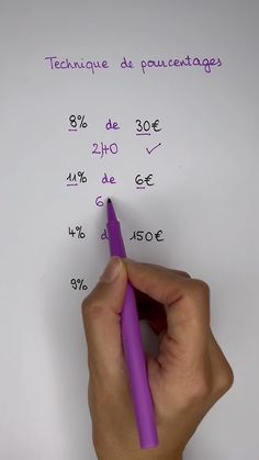 a hand holding a purple pen on top of a white piece of paper with writing