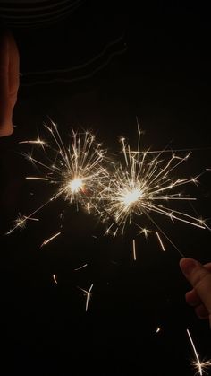 two people are holding sparklers in their hands as they look at the firework