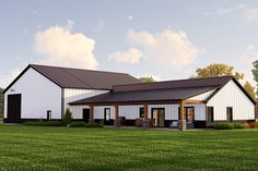 a large white barn sitting on top of a lush green field