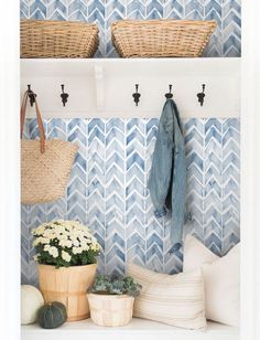 a blue and white tiled wall with baskets on the shelf next to flowers, plants and other items