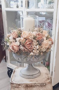 a vase filled with lots of flowers on top of a table next to a window