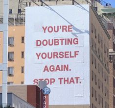 a large sign on the side of a building that says you're doubting yourself again again stop that