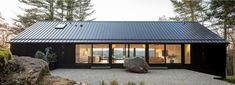 a house with a large rock in front of it and trees around the outside area