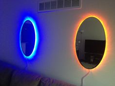 two round mirrors on the wall above a couch with a blue light in front of them