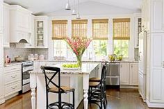 a kitchen with white cabinets and an island in the middle, surrounded by wooden flooring