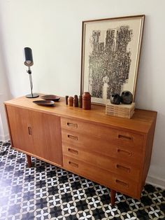 a wooden dresser sitting on top of a black and white checkered floor next to a painting