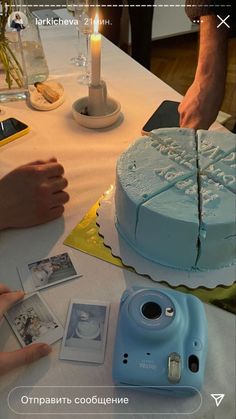 a blue cake sitting on top of a table next to a person holding a camera