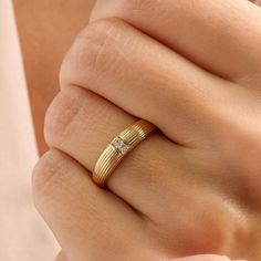 a woman's hand wearing a gold ring with two diamonds on the middle and side